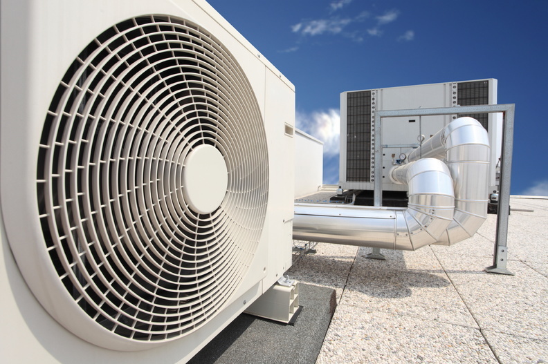 Technician repairing rooftop AC units for consistent cooling in commercial buildings